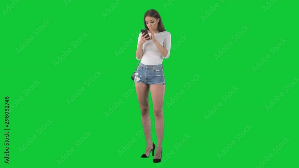 Young woman surfing net browsing and using cellphone displeased. Full body isolated on green screen chroma key background Young woman surfing net browsing and using cellphone displeased. Full body isolated on green screen chroma key background