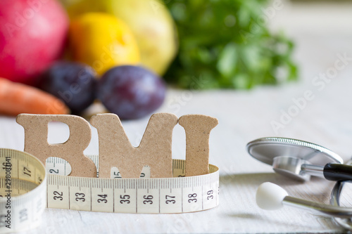 Body mass index BMI with measuring tape, stethoscope and fruits concept photo