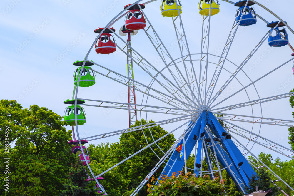Ferris wheel without people , among green on the blue sky background Ferris wheel without people , among green on the blue sky background