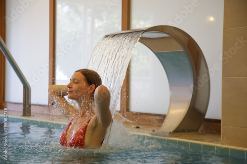 Obraz na plátně Woman enjoying hydrotherapy and water stream in spa pool