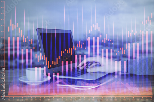 Double exposure of businessman's hands with laptop and stock market graph background. Concept of research and trading.
