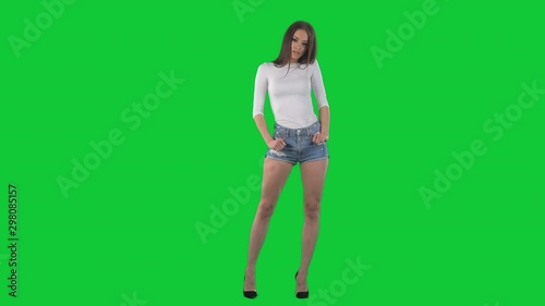 Young attractive cocky multi ethnic girl turning from side to front with hand in pockets.  Full body isolated on green screen chroma key background	