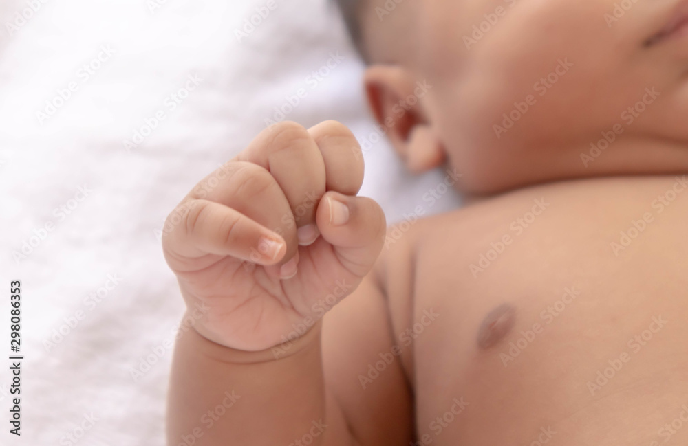 Newborn baby holding father's finger While sleeping comfortably on the white mattress During bedtime, the child's brain will work. To enhance Memory-boosting and learning-building skills