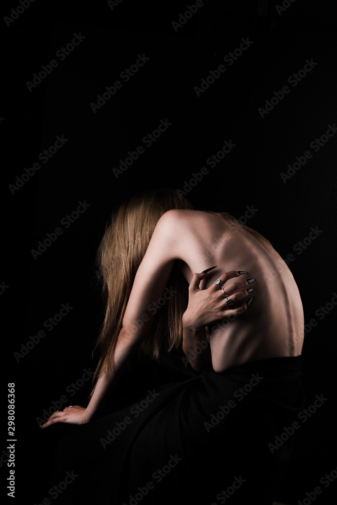 A girl with a bare back, severe thinness and protruding ribs. The concept of anorexia and bulimia, a disease of thin people. The struggle of the evil spirit in a girl, suffering and poverty.