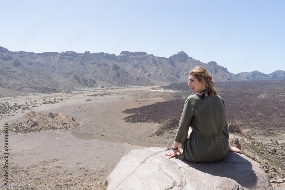 Happy tourist sitting in a rock of a viewpoint,with observation and relax in a volcanic desert at 