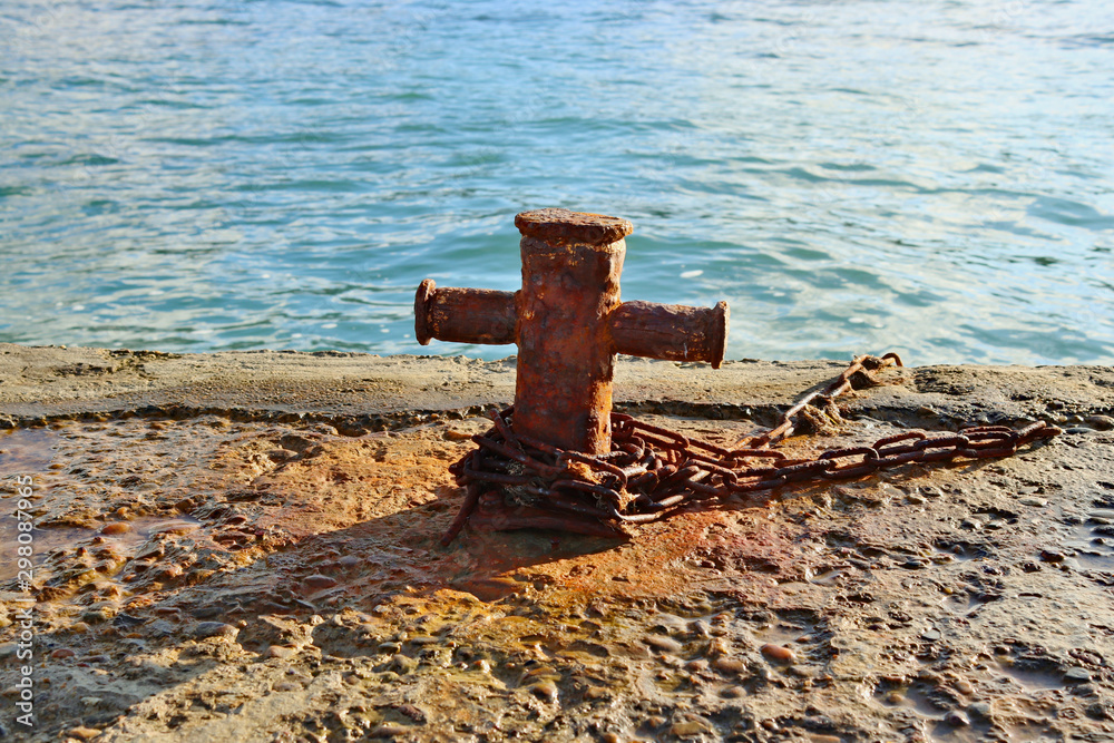 Naklejka premium Rusty bit with a chain on a stone pier