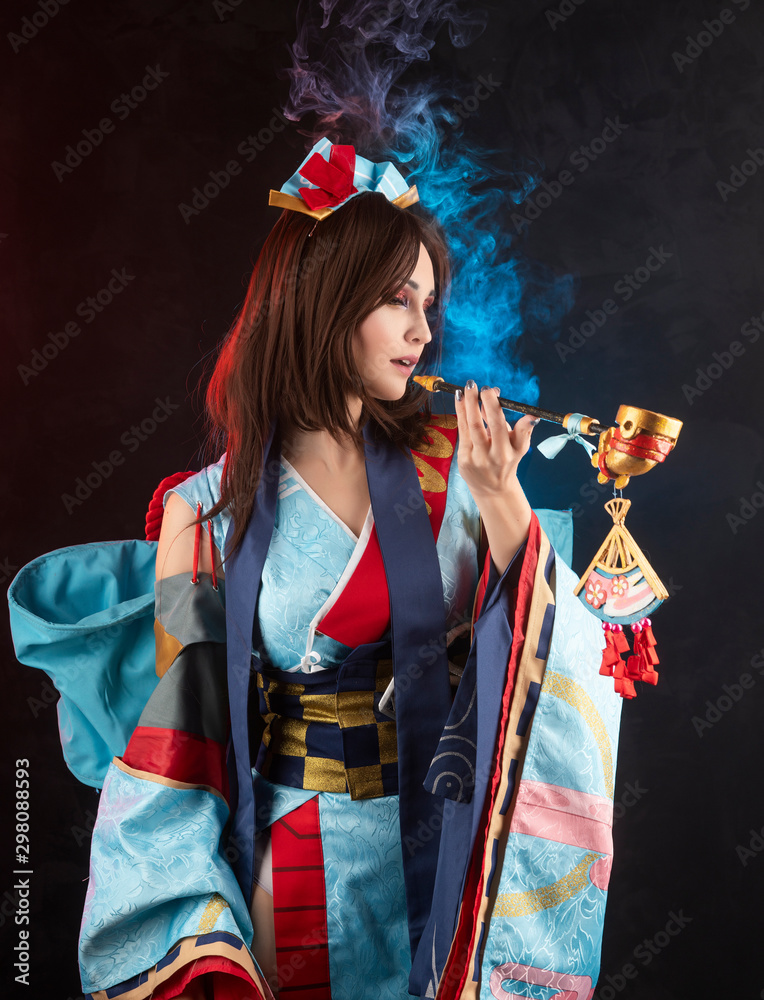 Beautiful leggy busty cosplay girl wearing a stylized Japanese kimono  costume posing smoking holding a fake pipe on a dark background. Photos |  Adobe Stock