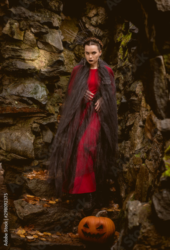 woman witch in red dress in a medieval castle.The medieval queen. Evil witch