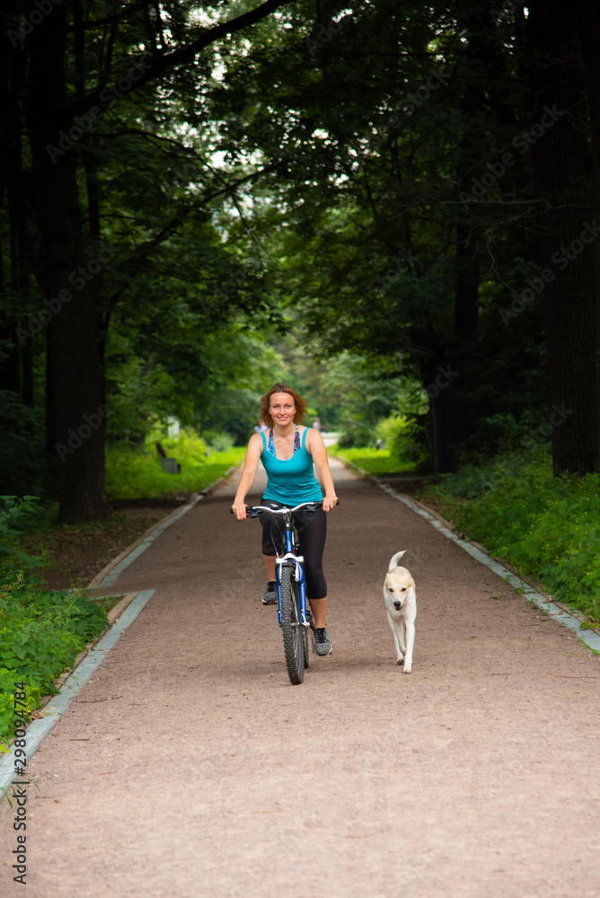 Fototapeta premium Girl on a bike ride with a dog