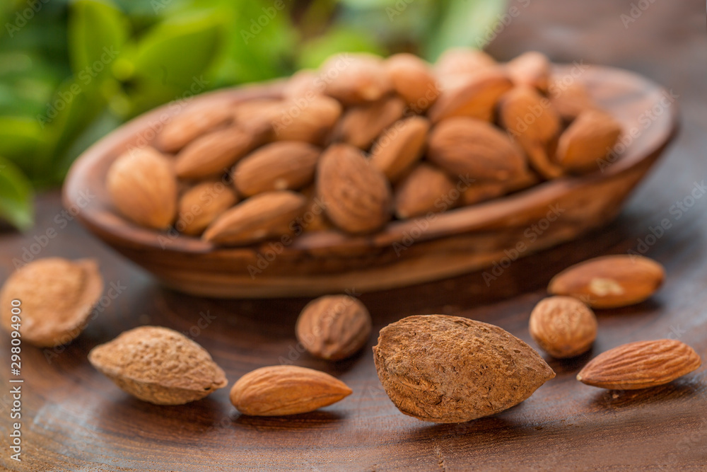 Almonds in wooden bowl on wooden table.