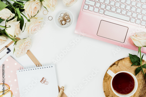 Stylish flatlay frame arrangement with pink laptop, tea, roses, glasses and other accessories on white. Feminine business mockup, copyspace