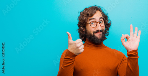 Canvas Print young bearded crazy man feeling happy, amazed, satisfied and surprised, showing