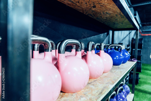 Set of colorful kettlebells on shelves in modern health club photo