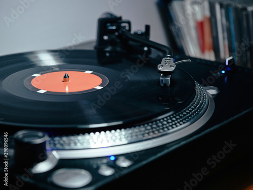 Closeup of top of old black turntable with tonearm maintaining position of cartridge tracing groove and playing LP record photo