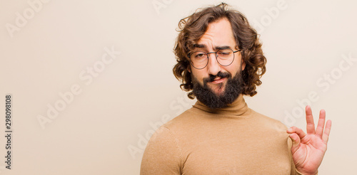 Fototapeta young bearded crazy man looking arrogant, successful, positive and proud, pointi