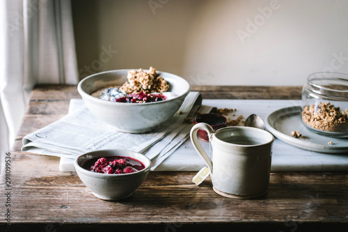 Delicious breakfast bowl with quinoa, rice and groats near tea cup and newspaper