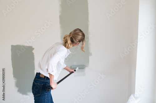 Woman rolling gray paint onto wall