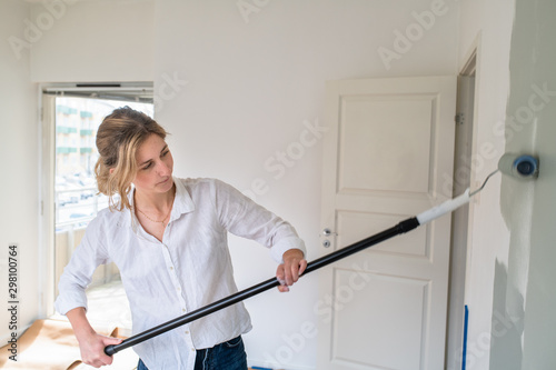 Woman rolling paint onto wall