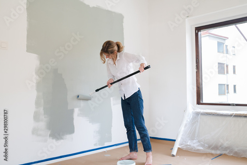 Woman rolling paint onto wall