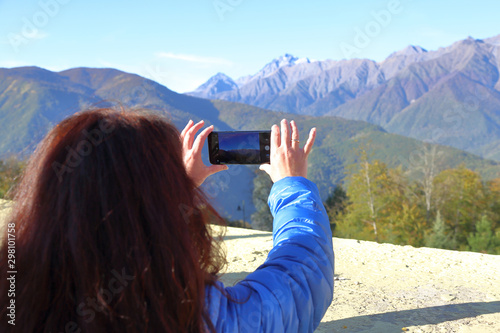 Brown-haired girl in a blue jacket admires the mountain landscape