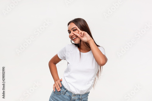 Beautiful african-american teenager in a white t-shirt and blue jeans dancing isolated over white background.