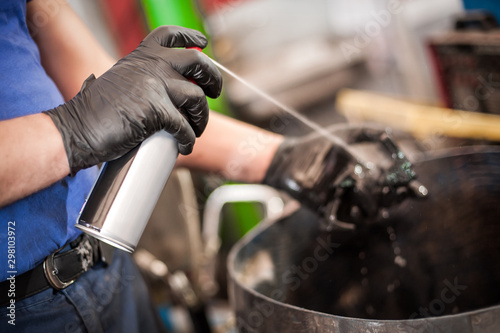 Car master mechanic repairer lubricates screws with machine cleaner spray
