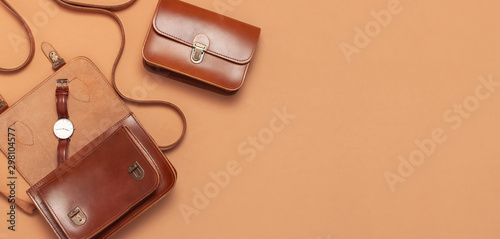 Brown leather women bag, stylish wristwatch on brown beige background top view flat lay copy space. Fashionable women's accessories. Sales Fashion Concept. Stylish Lady Clothes. Luxury Leather Bag