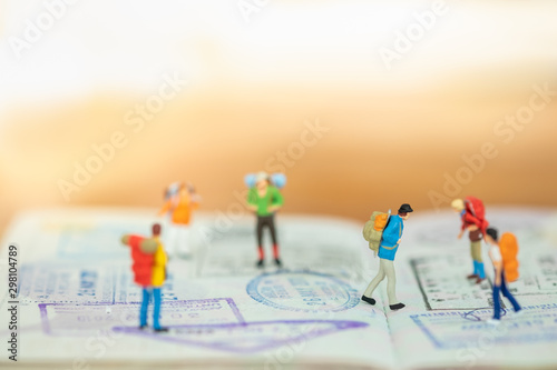 Travel Concept. Close up of group of traveler miniature figure with backpack walking and standing on passport with immigration stamped and copy space.