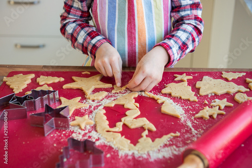 Close up of childs hands making christmas ginger cookies of different forms in kitchen