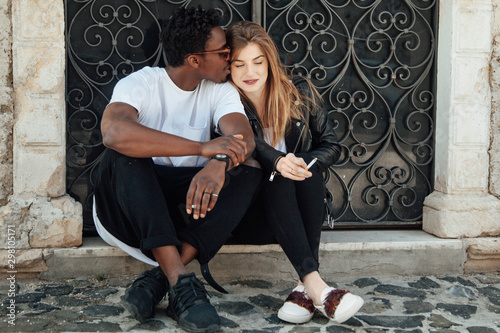 Attractive interracial Young Black and White Couple, Smoking a Cigarettes photo