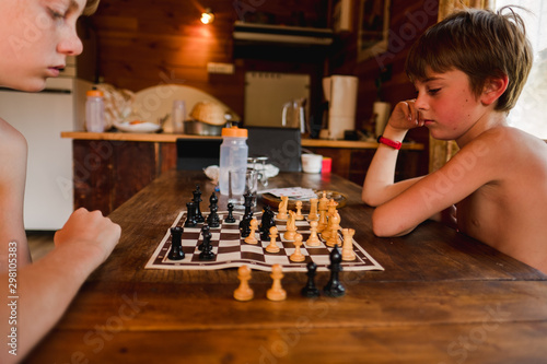 two kids playing a game of chess in the summer in a chalet photo