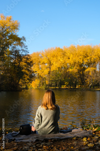 Autumn girl sitting backwards on lake and forest  © NKTN