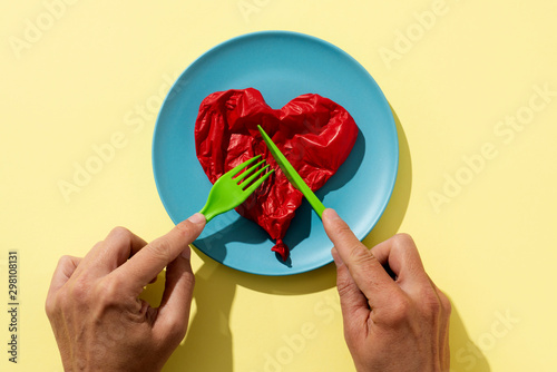 man eating a deflated red balloon