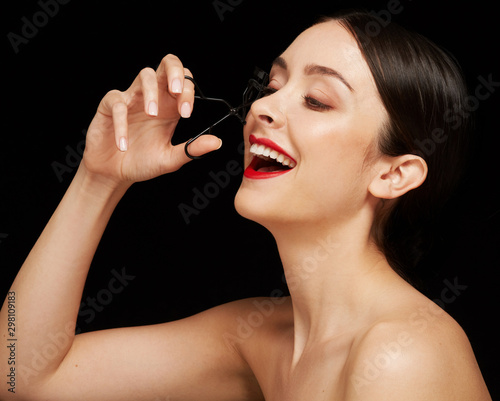 Classic editorial portrait woman using eyelashes curler photo