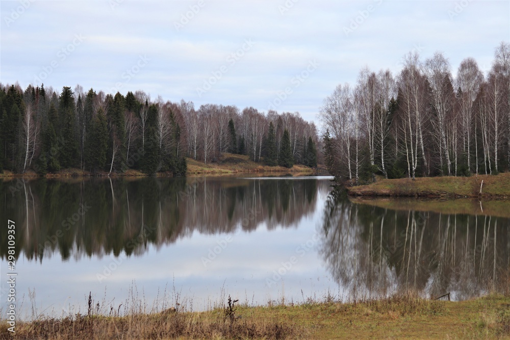 Fototapeta premium Autumn landscape: a forest lake, around which a mixed forest grows.