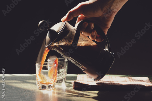 Aromatic coffees with hot smoke are poured into couple cup from French press coffee maker, Hot drink is good for health,On old wood table,Black background,Natural light,Selective focus,Vintage style.
