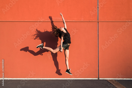 Woman jumping against a red wall photo