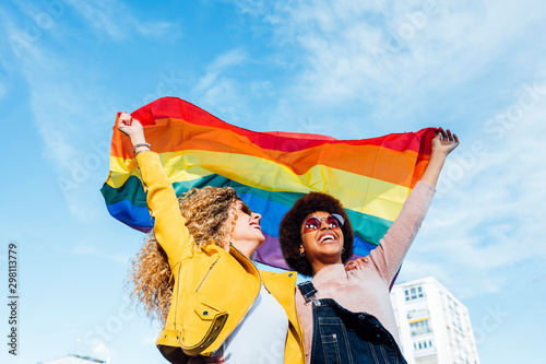 Two women friends hanging out in the city waving LGBT with pride flag photo