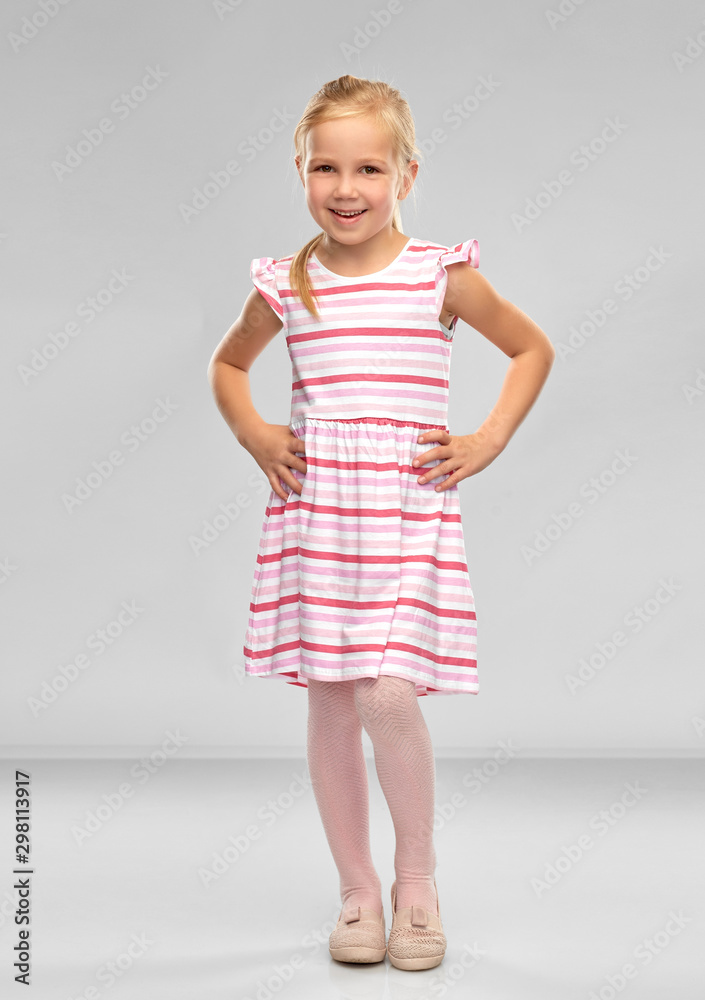 childhood and people concept - smiling little girl in striped dress over grey background childhood and people concept - smiling little girl in striped dress over grey background
