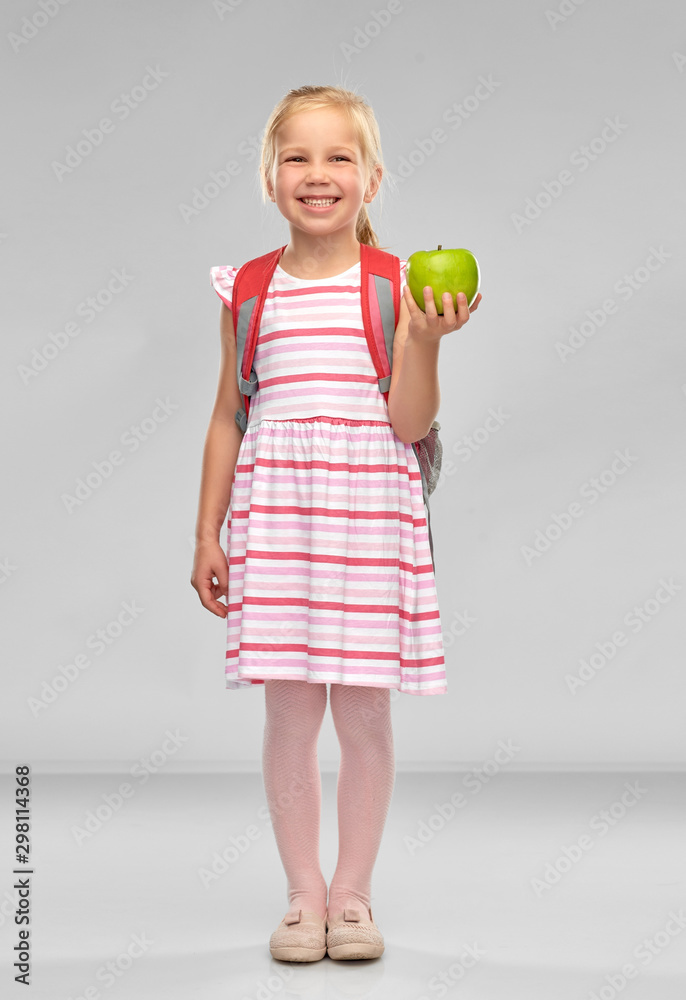 childhood, education and knowledge concept - little student girl with school bag and green apple over grey background childhood, education and knowledge concept - little student girl with school bag and green apple over grey background