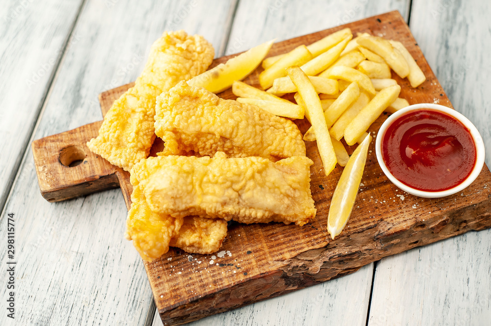Naklejka premium fish and chips with french fries, on wooden background