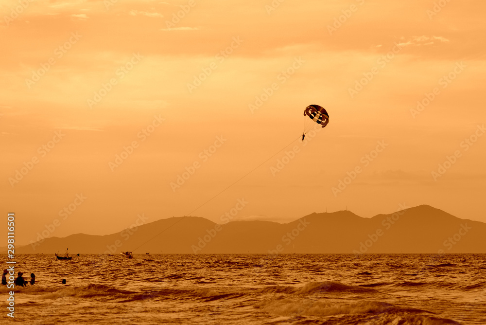 Parasailing in the evening sky near the coast of Vietnam. Orange color toned