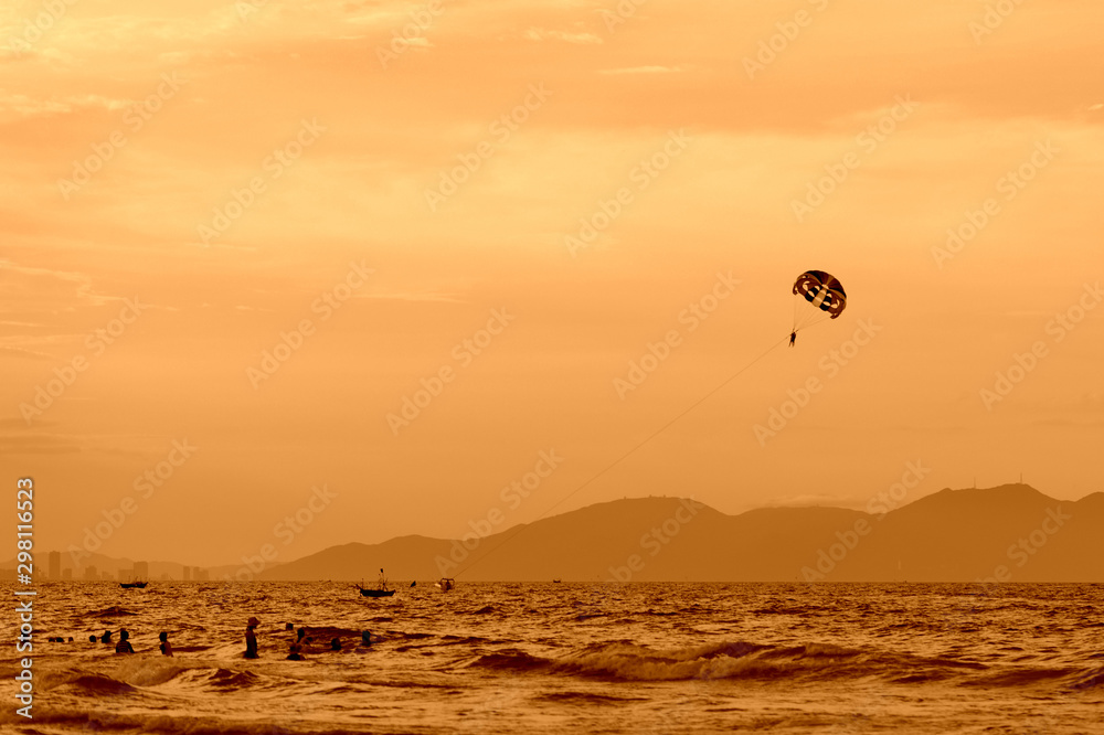 Parasailing in the evening sky near the coast of Vietnam. Orange color toned Parasailing in the evening sky near the coast of Vietnam. Orange color toned