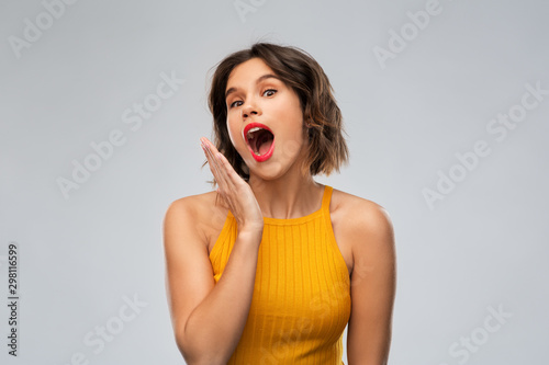 emotions, expressions and people concept - surprised young woman in mustard yellow top over grey background