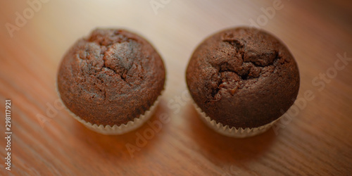 two chocolate muffins on the brown wooden table.