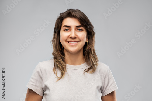 fashion, jewelry and people concept - happy smiling young woman in grey t-shirt and golden earrings