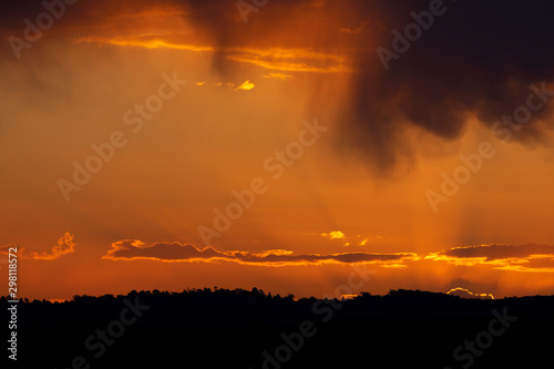 A vivid orange sunset in The Blue Mountains in Australia with a valley and trees in the foreground.