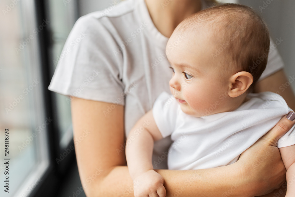 family, child and parenthood concept - close up of young mother holding little baby daughter over grey background family, child and parenthood concept - close up of young mother holding little baby daughter over grey background
