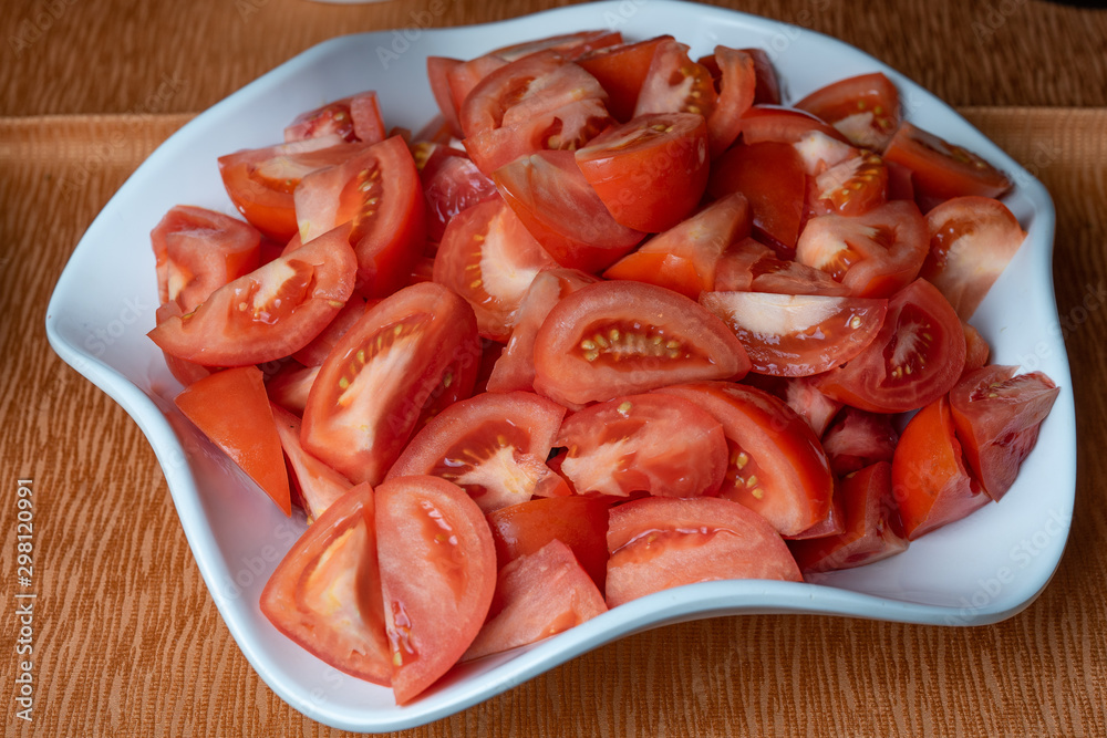 Fresh tomatoes cut into pieces in a plate Fresh tomatoes cut into pieces in a plate