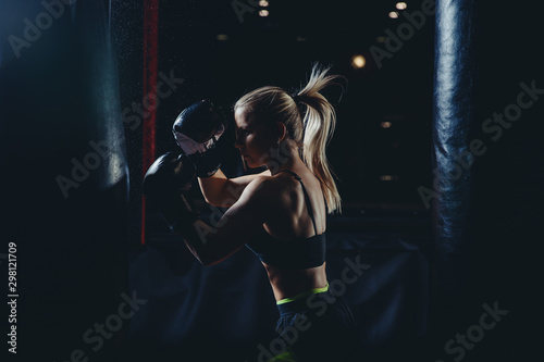 Strong athletic young blond woman is training self-defense punches in boxing gloves. Concept female sport © Parilov